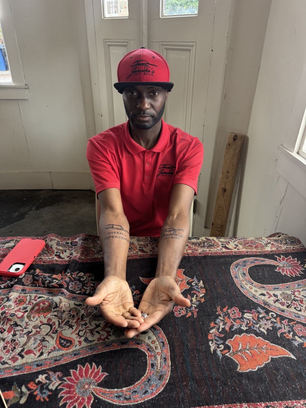 Jerode wearing his red Joy Ride uniform and showing his brand tattoos
