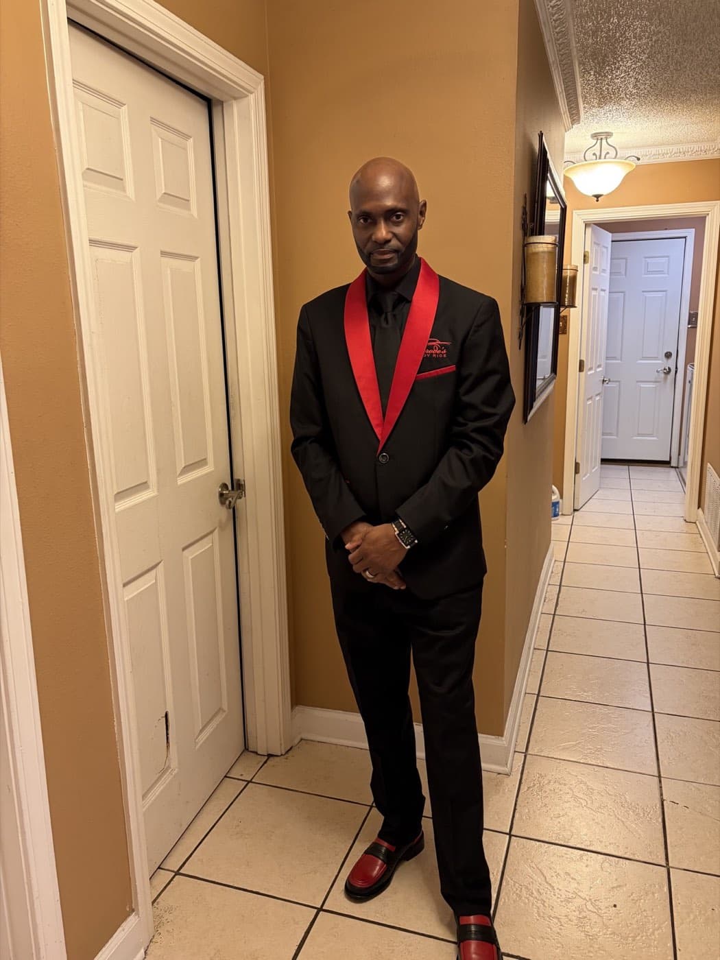 Jerode in a black chauffeur suit with red trim