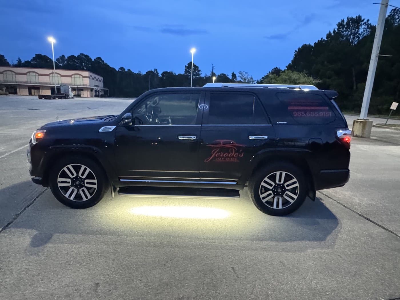 Black Joy Ride SUV with illuminated running boards at dusk