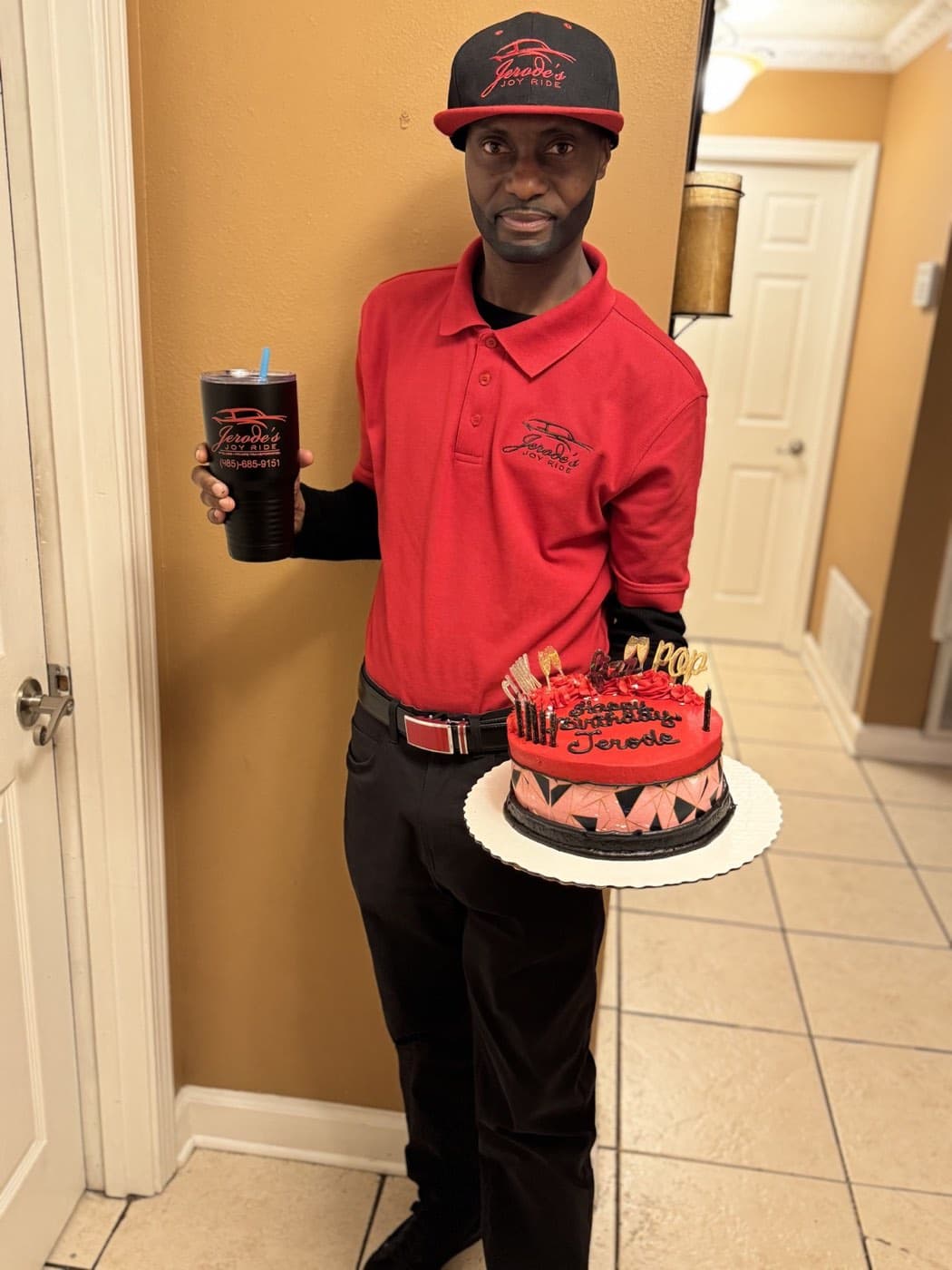 Jerode holding a Joy Ride anniversary cake and branded cup