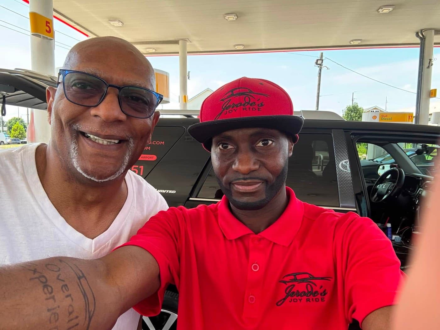 Jerode and a smiling rider taking a selfie beside the SUV